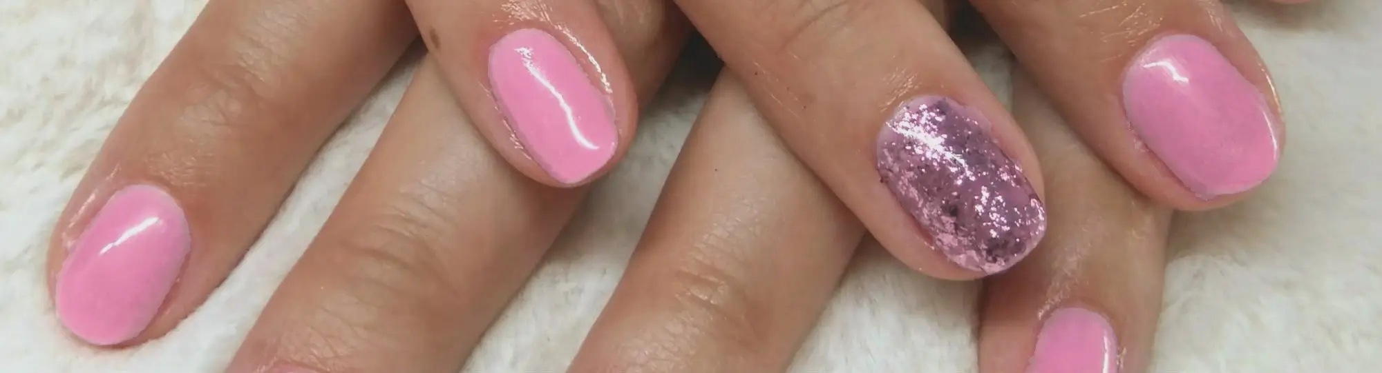 Close-up van twee handen met verzorgde nagels in roze gellak, één nagel met roze glitter.