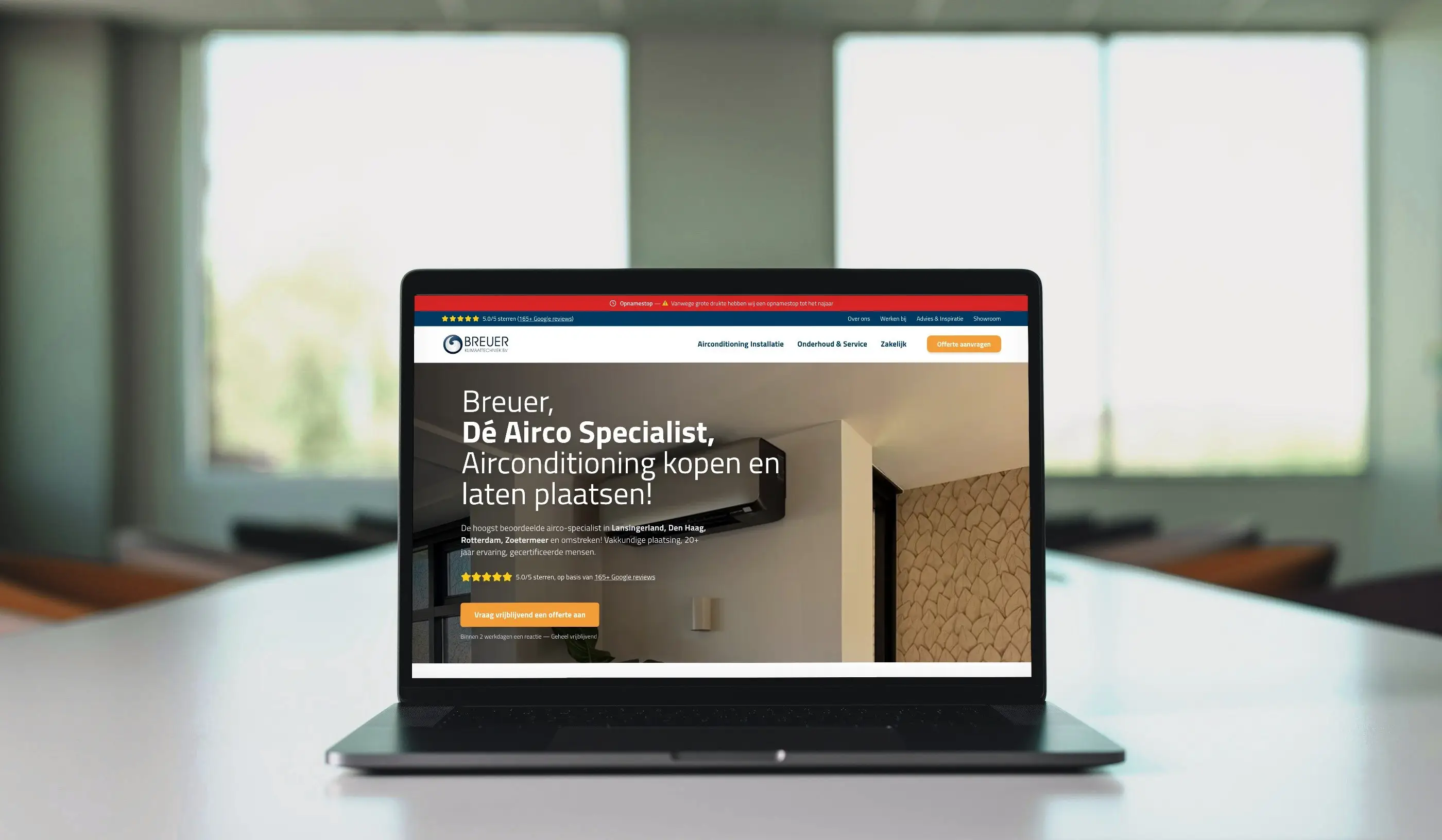 De website van Breuer Klimaattechniek op het scherm van een laptop op een witte vergadertafel.
